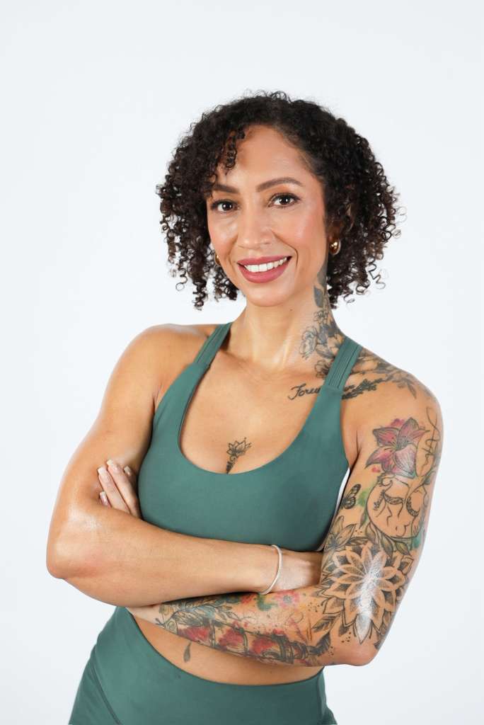 Flávia Ribeiro, personal trainer, sorrindo com os braços cruzados